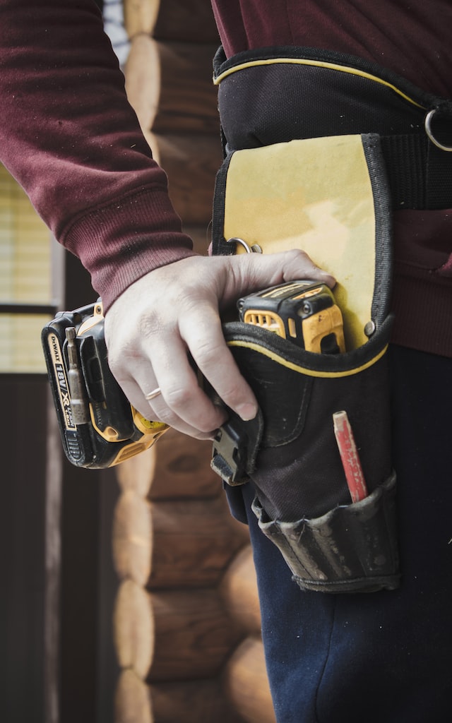 mans hand on power tool in side holster