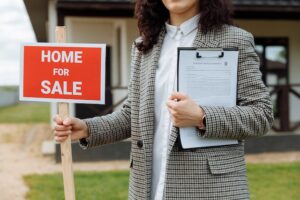 real estate agent holding a home for sale sign