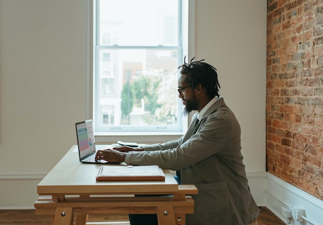 man in a suit typing into a laptop in a minimalistic home